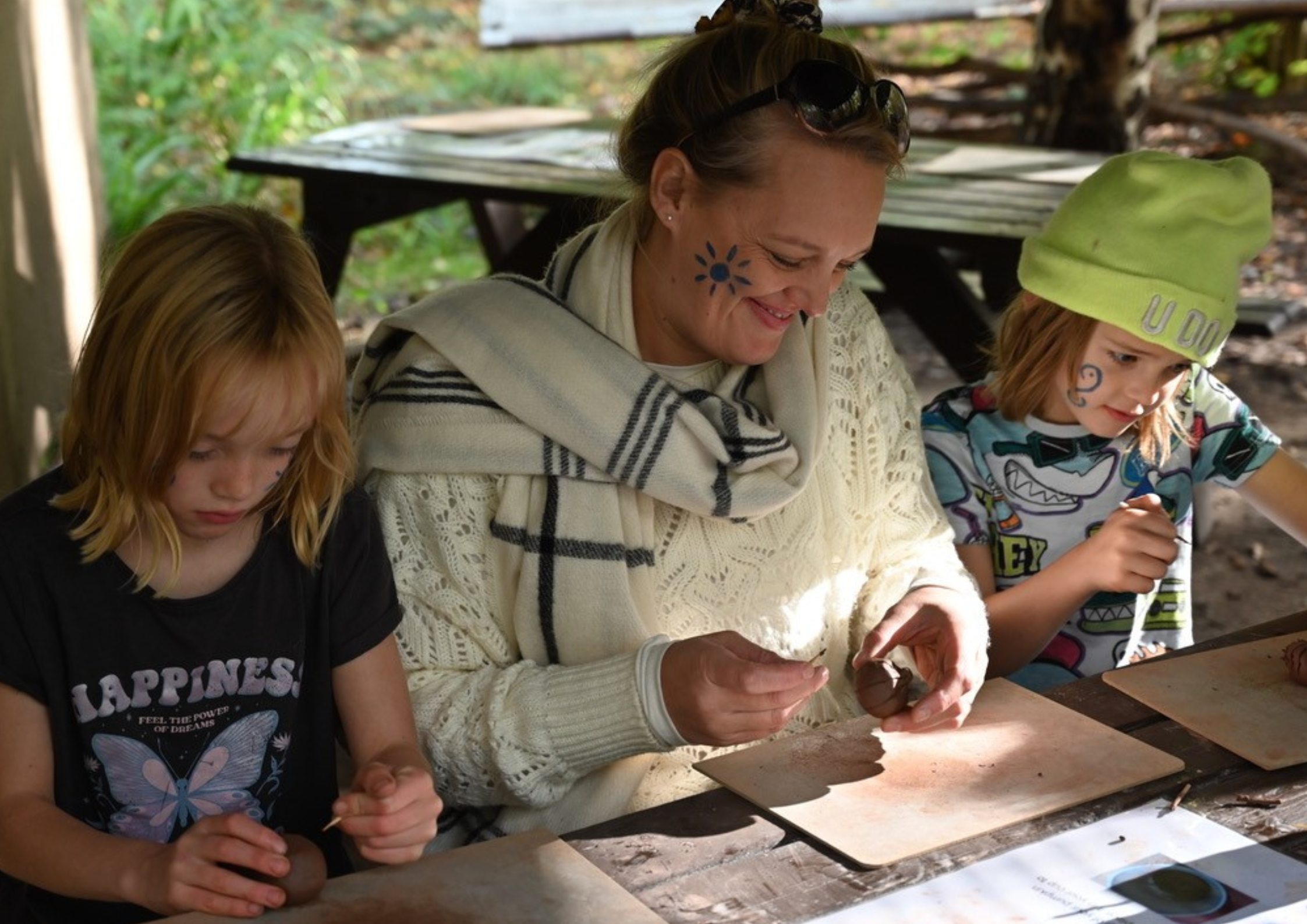 Adult and two children taking part in an arts and crafts activity sitting at a table