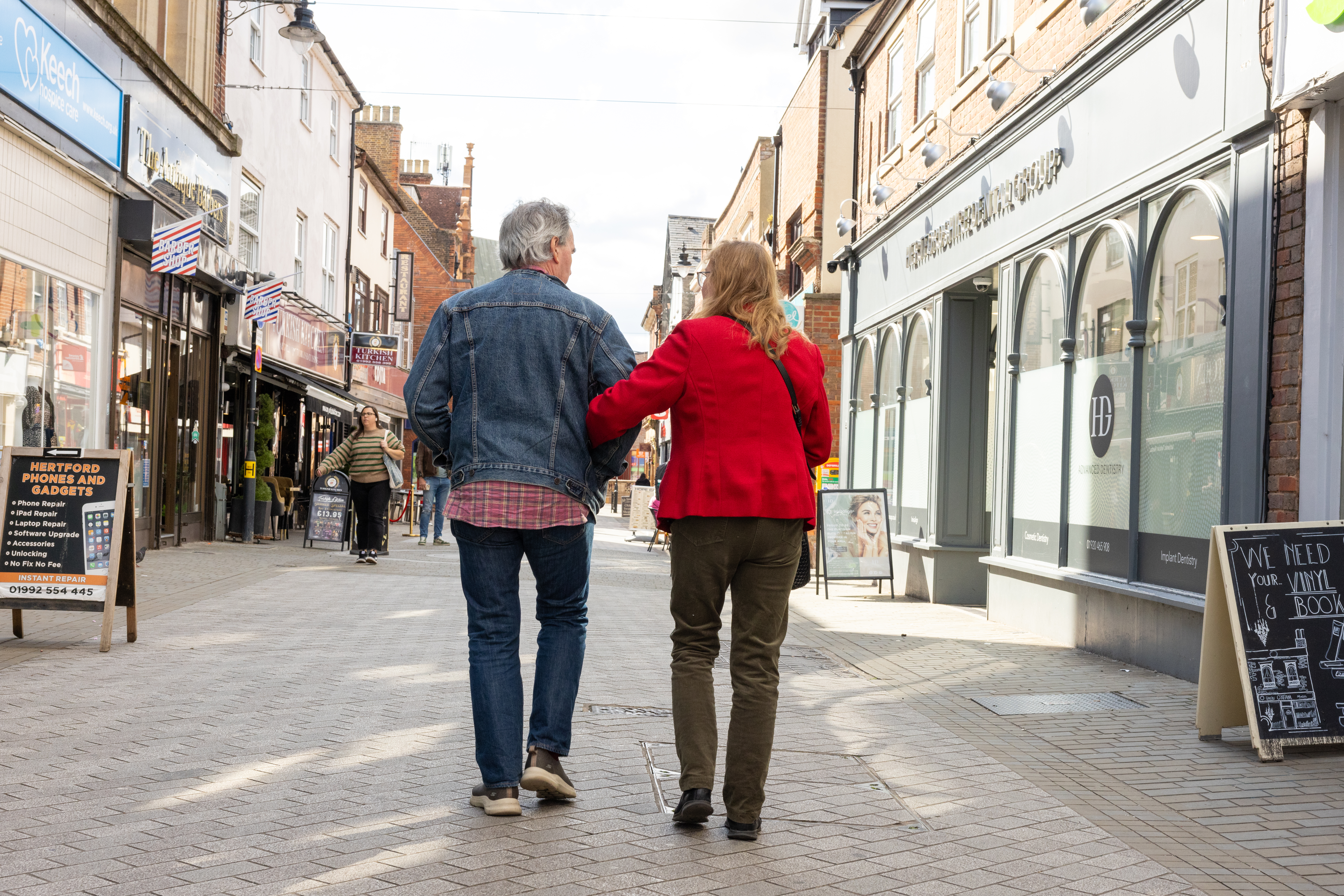 Couple walking arm in arm along high street