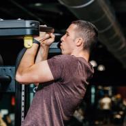 Man doing chin-up on equipment in gym