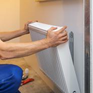 workman's hands installing radiator to wall