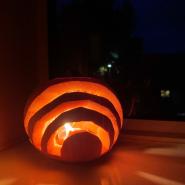 strips carved out of a pumpkin with candlelight showing through
