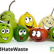 Different types of coloured fruit with smiling faces on a white background and with Love Food Hate Waste hashtag in black writing and Greener East Herts and East Herts Council logos