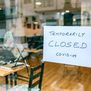 A shop window with a sign that says Temporarily Closed Covid-19