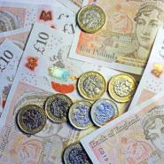 Ten pound notes laid out underneath pound coins