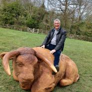 Eric Buckmaster sitting on the new hand carved Longhorn cow in Pishiobury Park