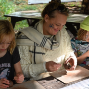 Adult and two children taking part in an arts and crafts activity sitting at a table