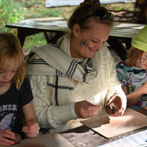 Adult and two children taking part in an arts and crafts activity sitting at a table