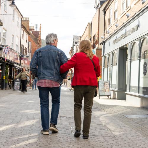 Couple walking arm in arm along high street